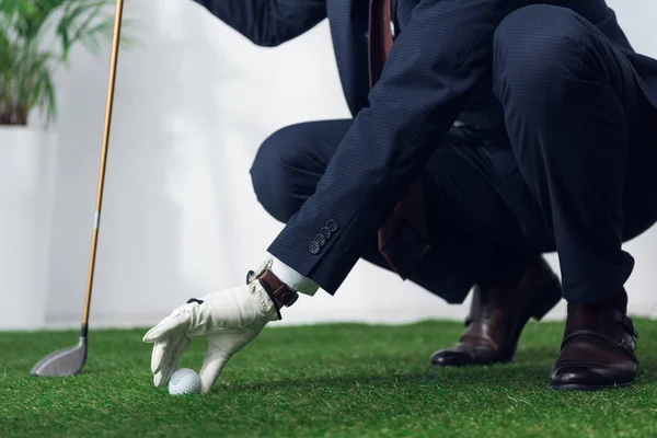 Cropped shot of businessman in suit and glove playing golf in office — Stock Photo