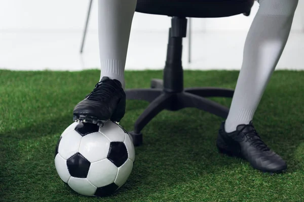 Recortado tiro de hombre de negocios en botas de fútbol con pelota de fútbol - foto de stock