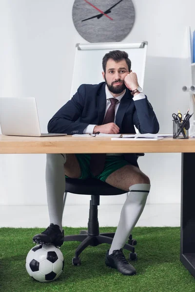Homme d'affaires fatigué avec ballon de football assis sur le lieu de travail dans le bureau — Photo de stock