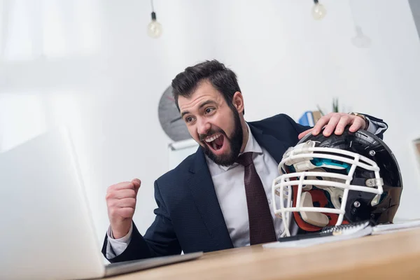 Uomo d'affari eccitato con casco da rugby sul posto di lavoro in ufficio — Foto stock