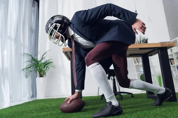 Вид збоку бізнесмена в регбі шолом грає в американський футбол в офісі — стокове фото