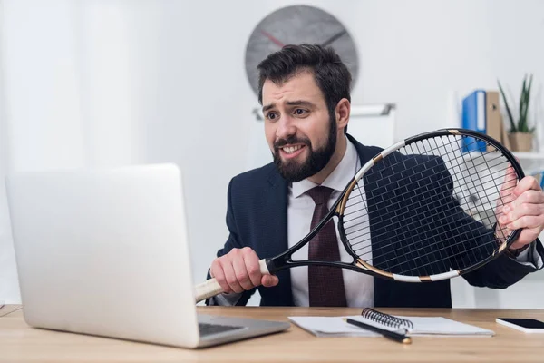 Businessman in suit with tennis racket at workplace — Stock Photo