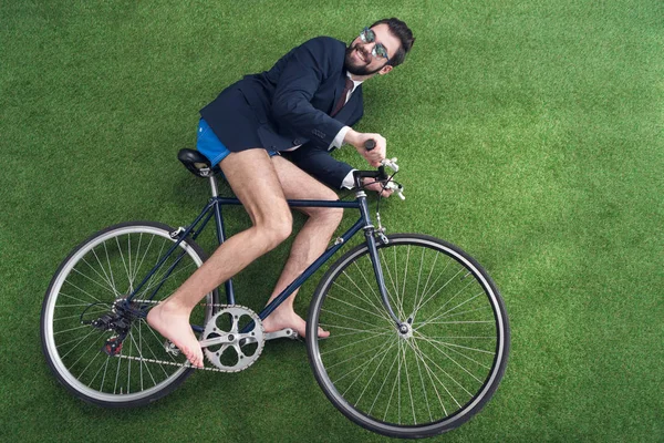 Blick auf Geschäftsmann, der auf grünem Rasen Fahrrad fährt — Stockfoto