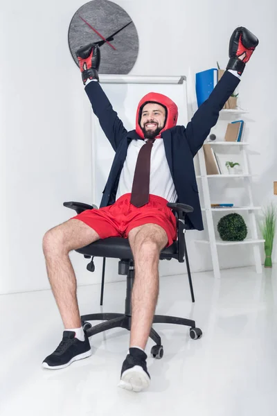 Porträt eines glücklichen Geschäftsmannes in Boxausrüstung, der im Büro auf einem Stuhl sitzt — Stockfoto