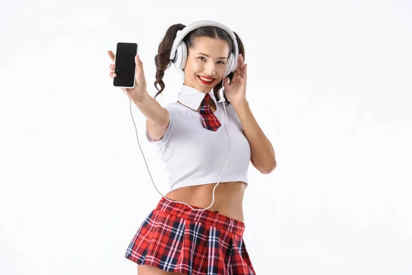 Sorrindo sexy estudante ouvir música com fones de ouvido e smartphone isolado no branco — Fotografia de Stock