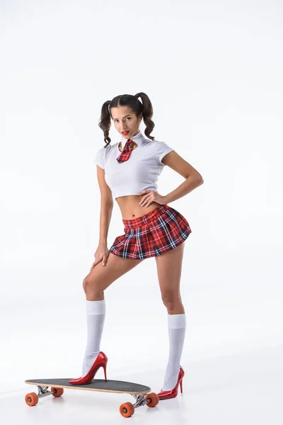 Joven sexy colegiala en rojo falda a cuadros con monopatín aislado en blanco - foto de stock