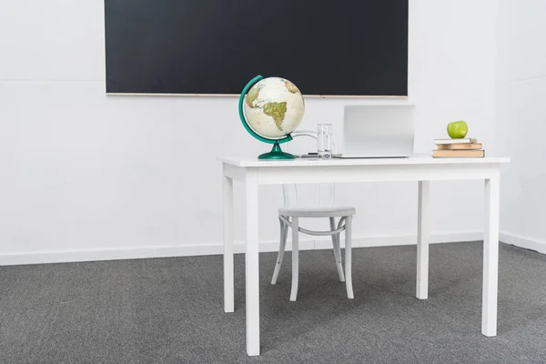 Teachers desk in classroom in front of blackboard — Stock Photo