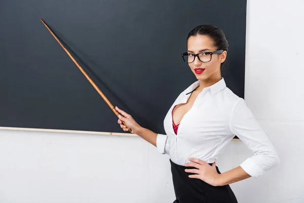 Jovem professor atraente apontando para quadro — Fotografia de Stock