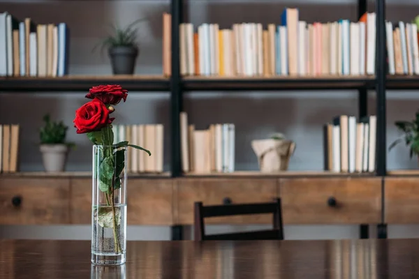 Beautiful red roses in vase at library — Stock Photo