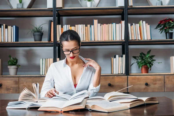 Giovane insegnante sexy in camicia sbottonata che legge in biblioteca — Foto stock