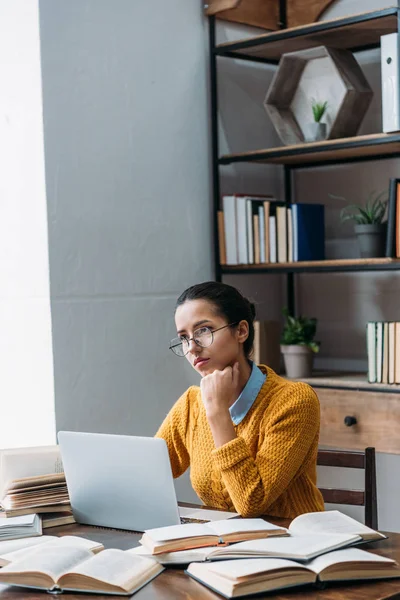 Thoughtful young student girl preparing for exam at library — Stock Photo