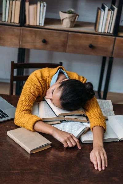 Überarbeitete Studentin schläft in Bibliothek, während sie sich auf Prüfung in Bibliothek vorbereitet — Stockfoto