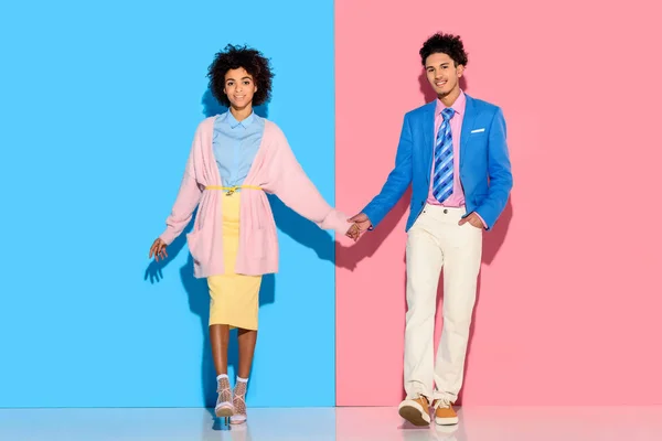 Happey couple holding hands on pink and blue background — Stock Photo