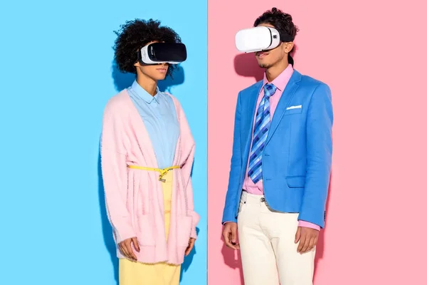 Portrait of african american couple in vr headsets against pink and blue wall background — Stock Photo