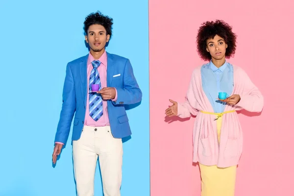 Elegante afroamericano con tazze da tè giocattolo con sfondo rosa e blu parete — Foto stock