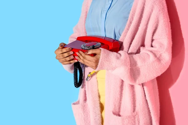 Частичный вид африканской американки, держащей в руках ретро-телефон с розовым и синим фоном — стоковое фото