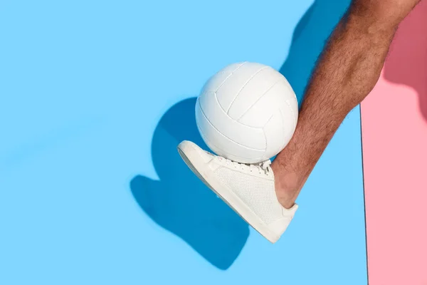 Cropped image of leg with ball  on pink and blue background — Stock Photo