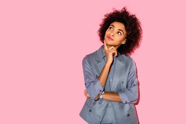 Young african amercian girl with hand on chin wearing grey suit on pink background — Stock Photo