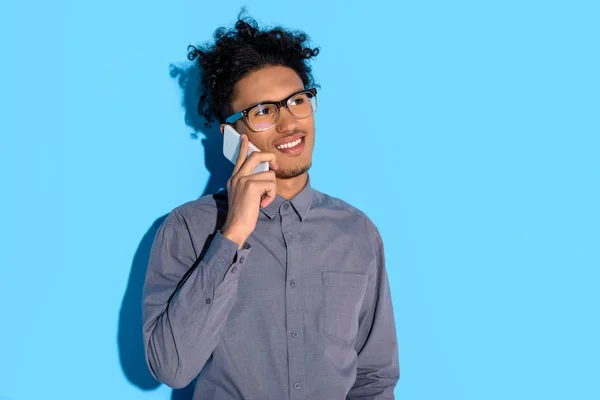 Young african amercian businessman talking on phone on blue background — Stock Photo