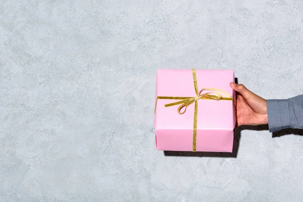 Close-up view of man giving gift box on grey background — Stock Photo