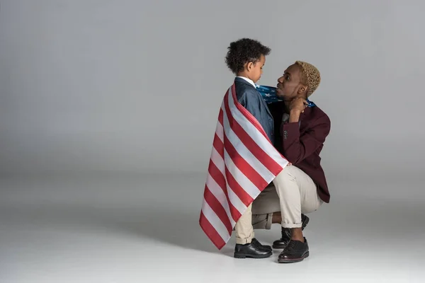 Família afro-americana envolta em bandeira em fundo cinza — Fotografia de Stock