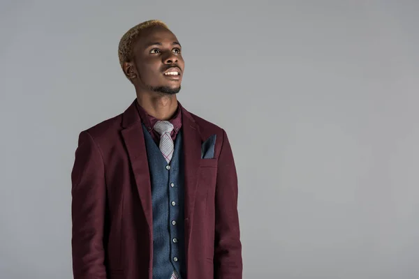 Smiling african american in jacket looking upwards isolated on grey — Stock Photo