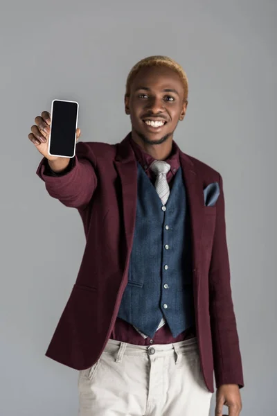 Sonriente hombre afroamericano con smartphone en mano aislado en gris - foto de stock