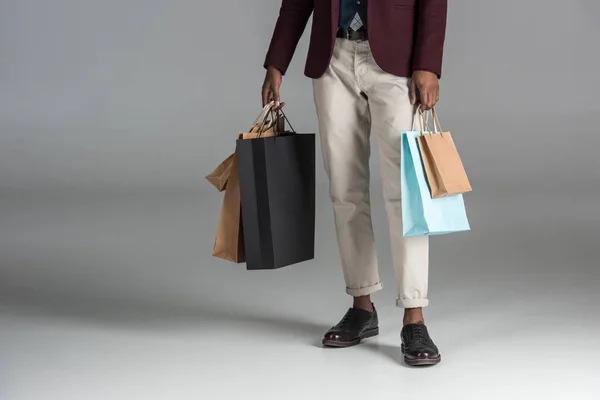 Low section of man with paper shopping bags on grey background — Stock Photo