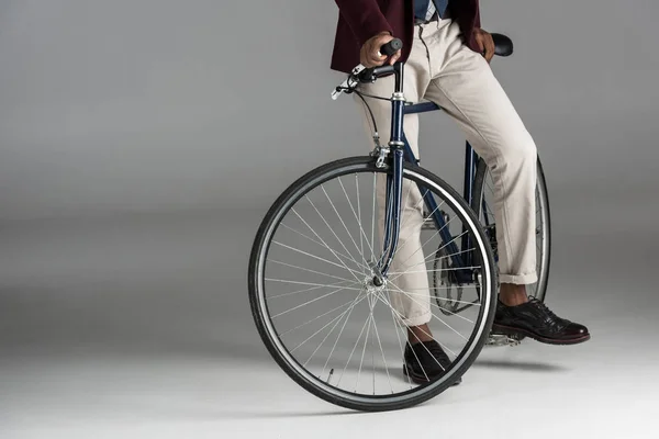 Низька частина людини сидить на велосипеді на сірому фоні — стокове фото