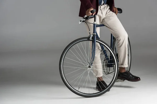 Baixa seção de homem situado na bicicleta em fundo cinza — Fotografia de Stock