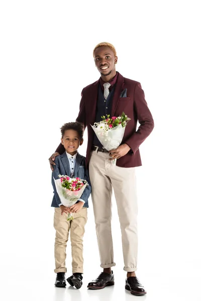 Yong african man and kid standing with flowers in hands isolated on white — Stock Photo