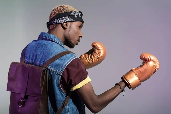 Young african american man in golden boxing gloves looking away isolated on grey — Stock Photo