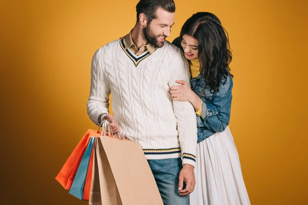 Glückliches Paar mit Einkaufstaschen isoliert auf gelb — Stockfoto