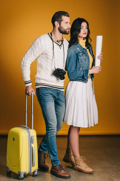Reisende mit Tasche auf Rädern schauen auf gelb weg — Stockfoto