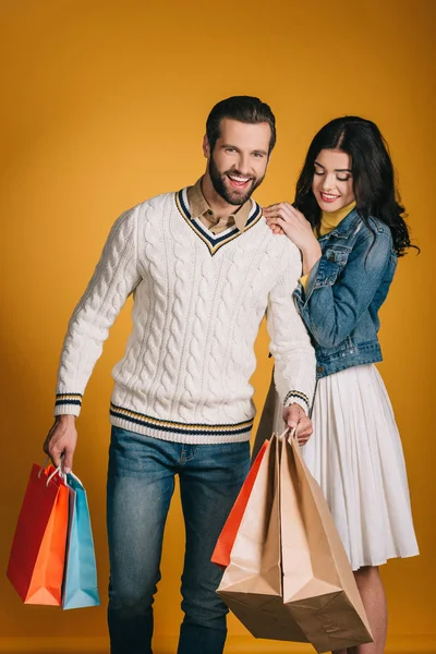 Couple heureux avec des sacs à provisions isolés sur jaune — Photo de stock