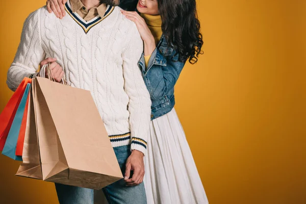 Imagem cortada de casal com sacos de compras isolados em amarelo — Fotografia de Stock