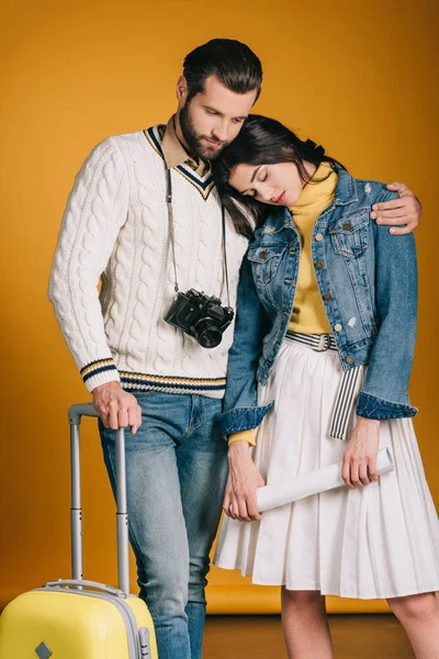 Tired couple of tourists with travel bag on yellow — Stock Photo