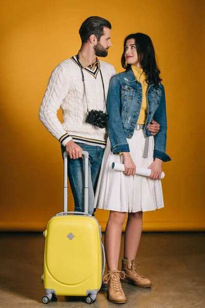 Happy couple of tourists with travel bag on yellow — Stock Photo