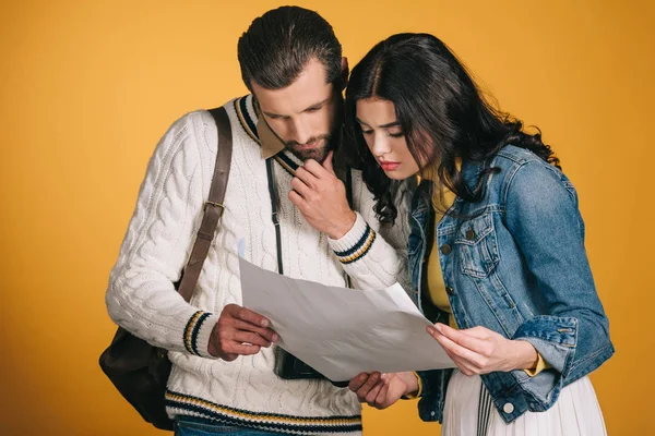 Casal de turistas olhando para mapa isolado em amarelo — Fotografia de Stock