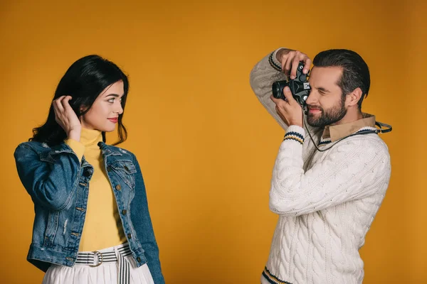 Namorado tirando foto de namorada com câmera de filme isolado no amarelo — Fotografia de Stock