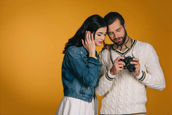 Boyfriend showing film camera to girlfriend isolated on yellow — Stock Photo