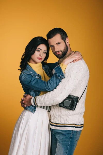 Парень и девушка обнимаются и смотрят на камеру, изолированную на желтый — стоковое фото