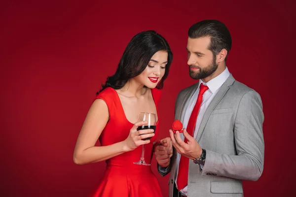 Novio haciendo propuesta a novia aislado en rojo - foto de stock