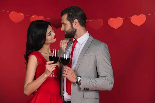 Couple with wineglasses looking at each other isolated on red — Stock Photo