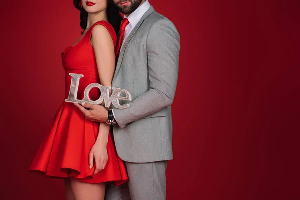 Abgeschnittenes Bild eines Paares, das mit Liebeszeichen isoliert auf Rot steht — Stockfoto