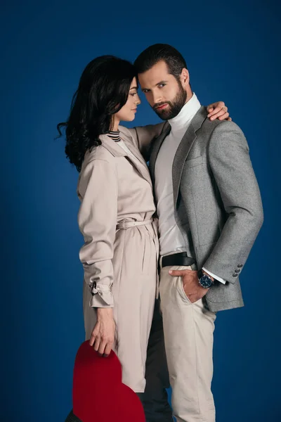 Paar hält herzförmigen Zettel in der Hand und umarmt sich isoliert auf blauem Grund — Stockfoto