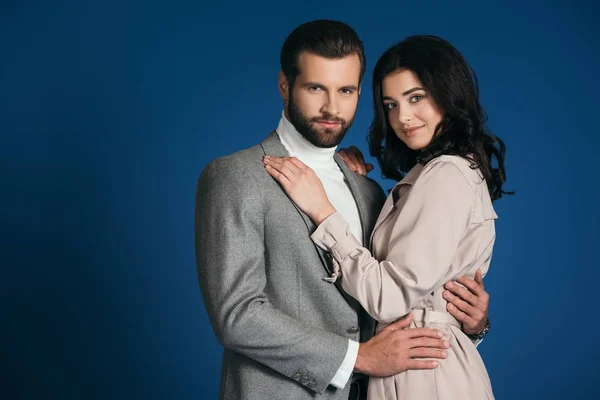 Attractive boyfriend and girlfriend hugging and looking at camera isolated on blue — Stock Photo