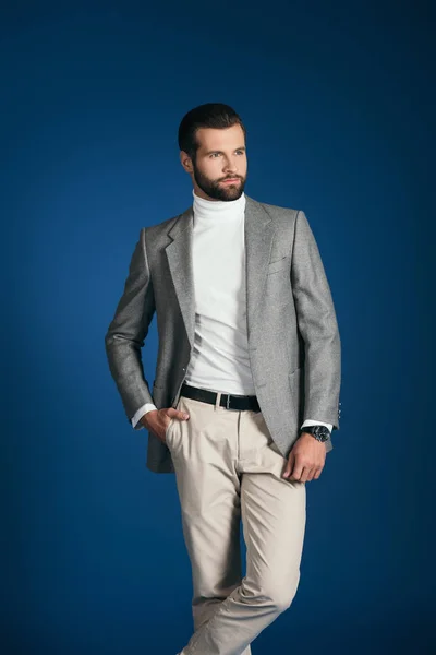 Handsome man standing in suit and looking away isolated on blue — Stock Photo