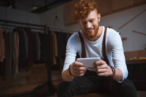 Souriant jeune créateur de mode masculin en utilisant smartphone sur le lieu de travail — Photo de stock