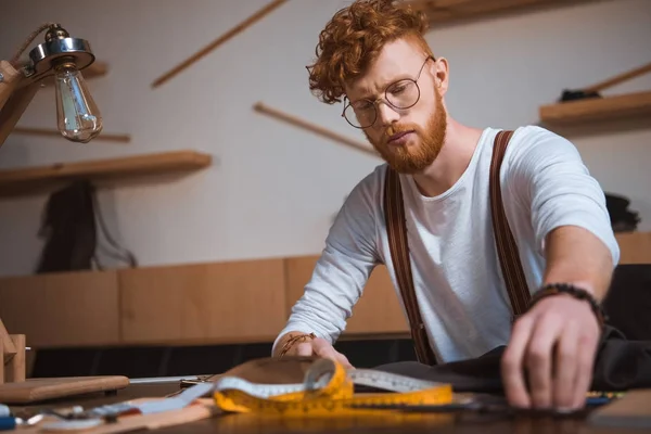 Foco jovem designer de moda trabalhando com tecido e fita métrica na oficina — Fotografia de Stock